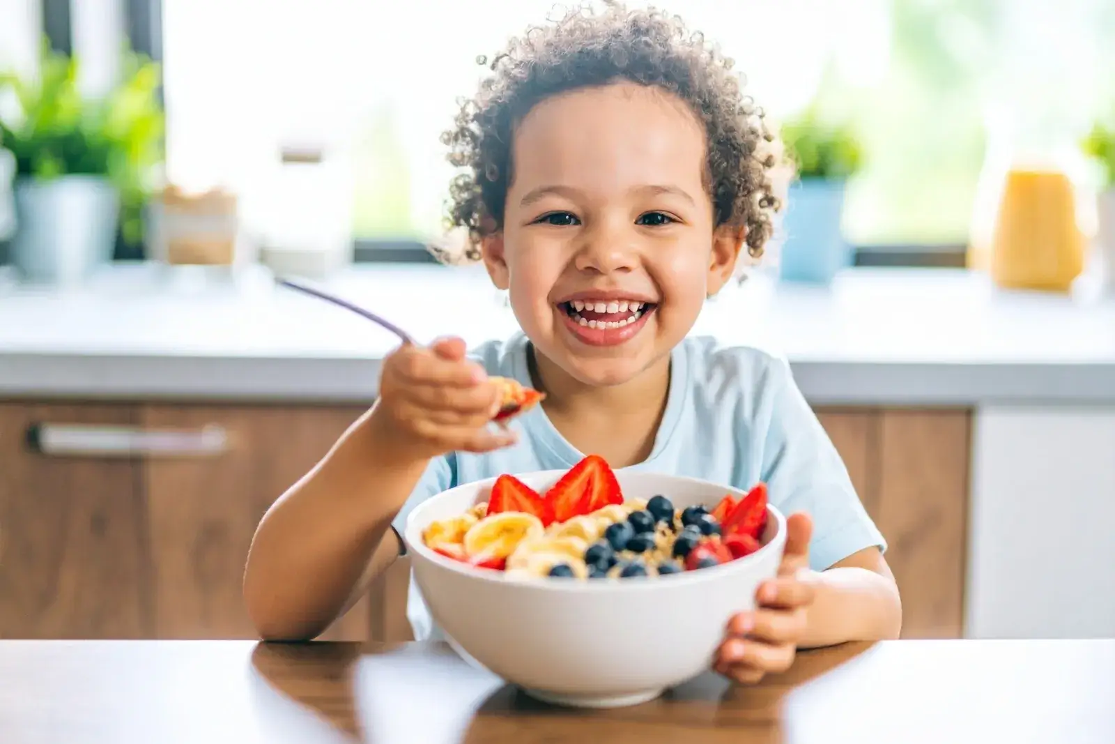 A happy child sitting at the table enjoying a healthy breakfast in a bright, clean, and organized home environment that supports routine, comfort, and family wellness.