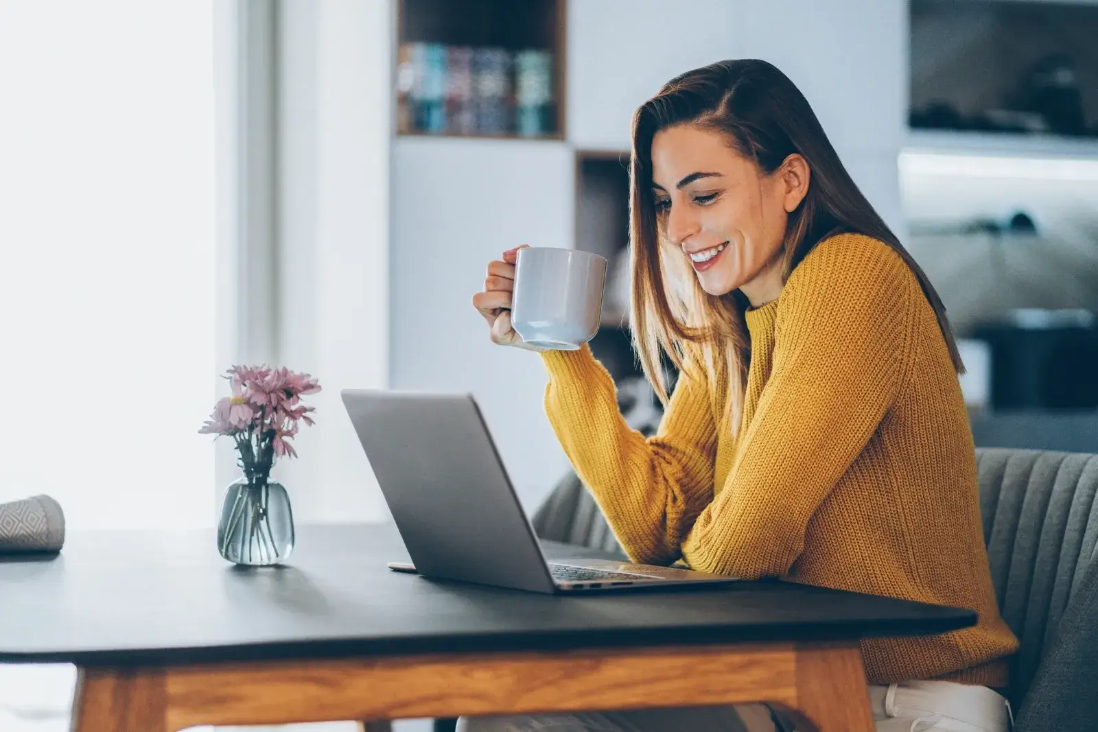 Woman working from home at a clean desk, enjoying coffee in an organized home workspace