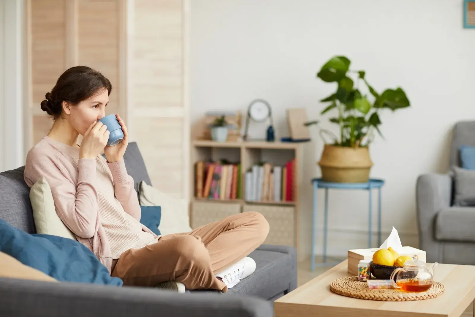 Woman resting on sofa at home, enjoying a calm and clean space during recovery