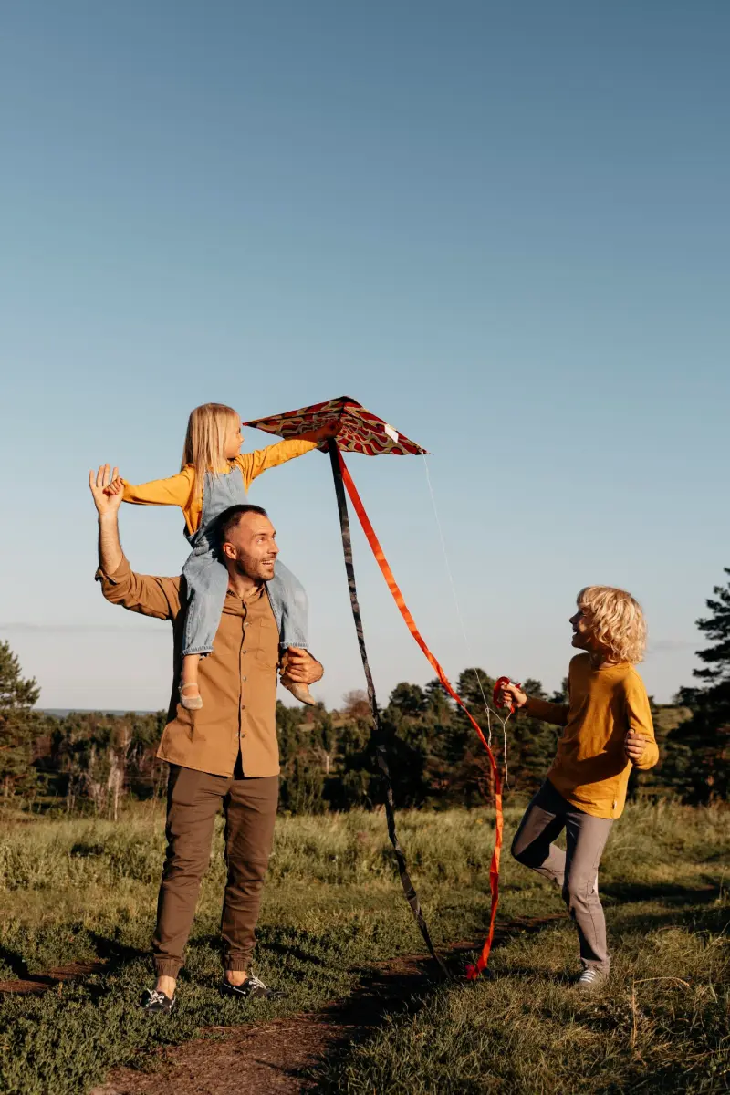 A man smiling and using his free time to play with his son and daughter in a park in Coto de Caza, CA.